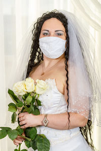 A jewish bride in a synagogue before a chuppa ceremony during a pandemic, wearing a medical mask 