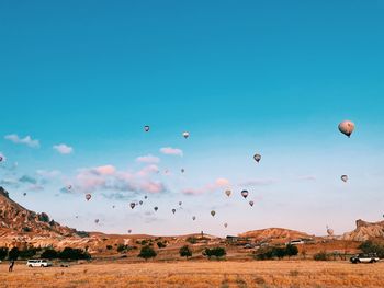Hot air balloons flying over land against blue sky