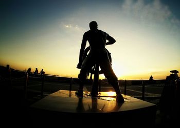 Silhouette of man with statue in city