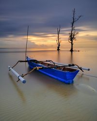 Fishing boat moored at sea against sky