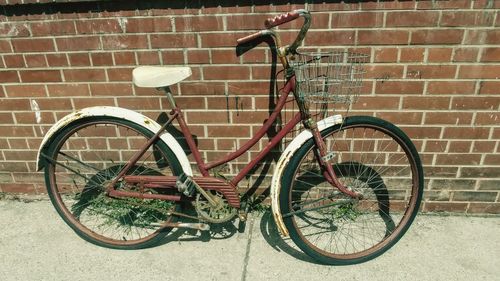 Bicycle parked against brick wall