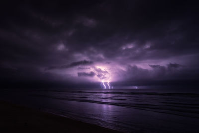 Scenic view of sea against dramatic sky at sunset