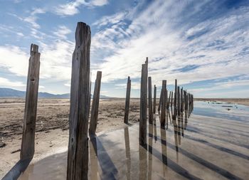 Wooden posts on beach against sky