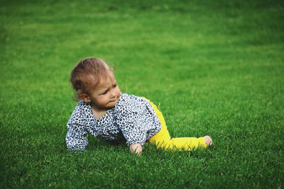 Portrait of cute baby crawling on green grass