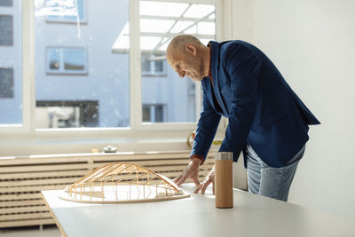 Architect looking at leaf shape wooden model in office