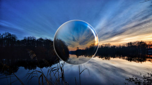 Reflection of trees in lake against sky at sunset