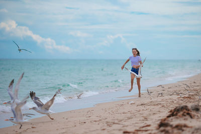 Full length of woman standing at beach against sky