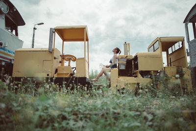 Side view full length of woman sitting on miniature train against sky