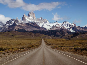 Road amidst snowcapped mountains against sky