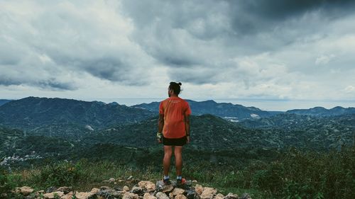 Rear view of man standing on mountain against sky