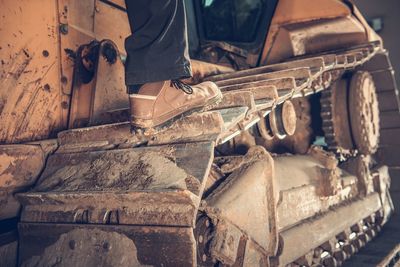 Low section of man on bulldozer wheel