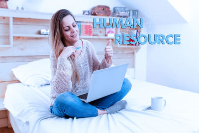 Young woman using phone while sitting on table