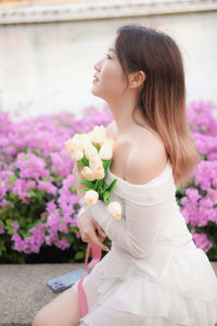Portrait of young woman standing by flowers