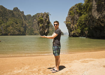 Optical illusion of man holding rock formation at beach