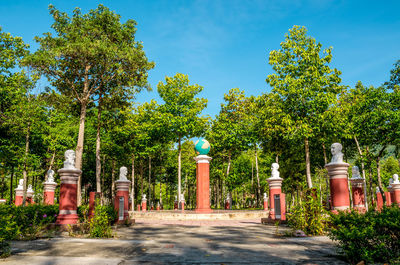 Street amidst trees and buildings against blue sky