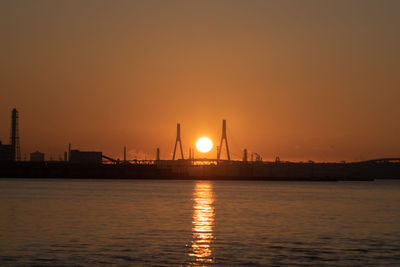 Silhouette of commercial dock against sky during sunrise