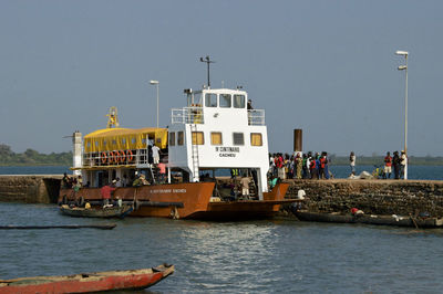 People at harbor against clear sky