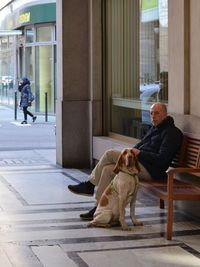 Man with dog sitting on bench in corridor