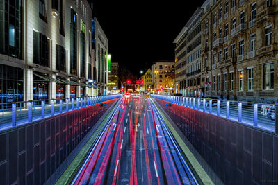 Light trails on road amidst buildings in city at night