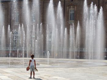 Rear view of boy standing against fountain