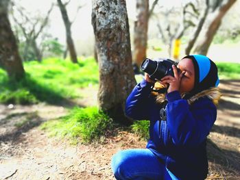 Full length of woman photographing camera on tree