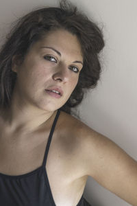 Portrait of beautiful young woman against wall