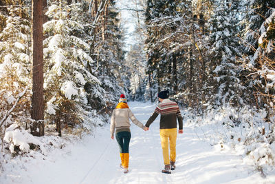 Rear view of people walking on snow covered land