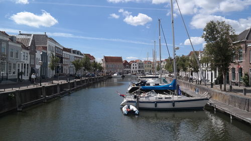 Sailboats moored on river by buildings in city