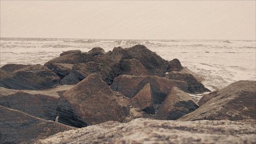 Rocks at sea shore against sky