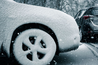 Close-up of snow covered car on road