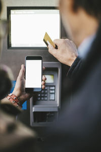 Senior couple making payment through credit card and smart phone at bike rental station