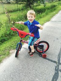 Portrait of boy riding bicycle on road