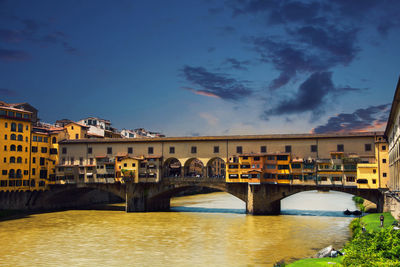 Bridge over river in city against sky