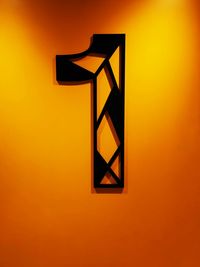 Low angle view of illuminated lamp against orange wall