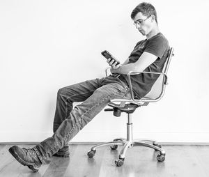 Young man using mobile phone while sitting on chair at home