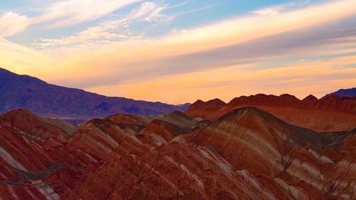 Scenic view of mountains against cloudy sky during sunset