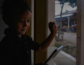 Boy looking through window at home