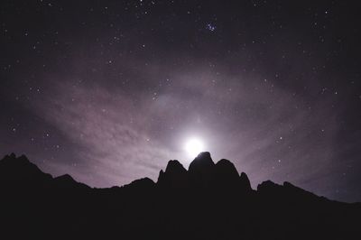 Low angle view of silhouette mountains against sky at night
