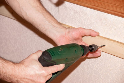 Close-up of man holding bottle against wall