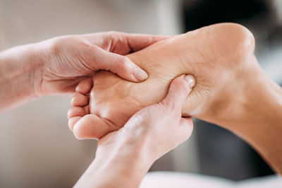 Cropped hands of massage therapist massaging female customer leg in spa