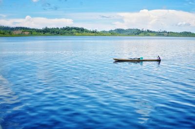 Man sailing in lake against sky