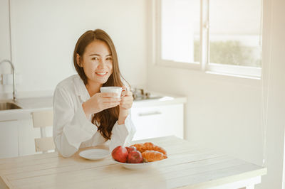 Young woman drinking coffee cup on table