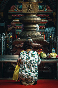 Woman praying in front of idol outside temple in building