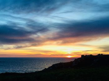 Scenic view of sea against dramatic sky during sunset