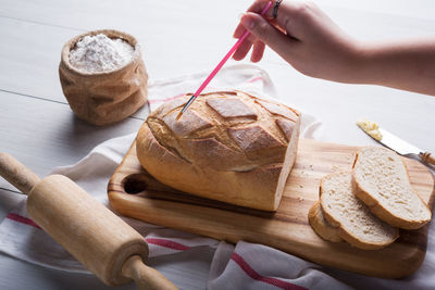 Cropped hand holding paintbrush over bread