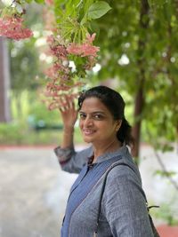 Portrait of young woman standing against trees