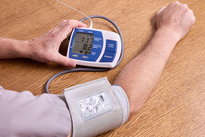 Cropped hand of person holding clock on table