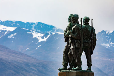 Statue in front of snowcapped mountains against sky