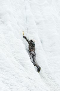 Low angle view of man climbing on snowcapped mountain