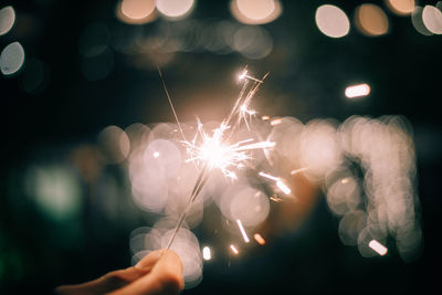 Close-up of person holding sparkler at night